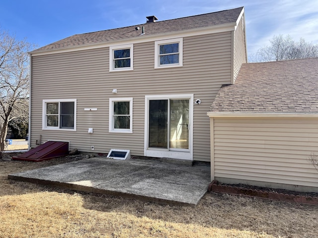 back of property with a shingled roof and a patio