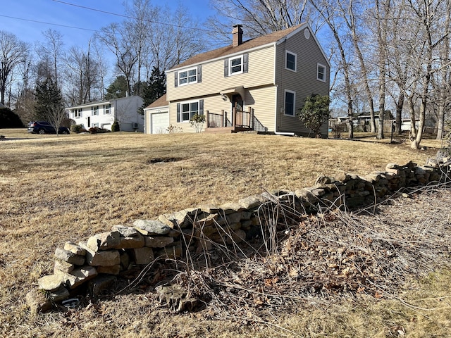 back of house with a garage, a chimney, and a shingled roof