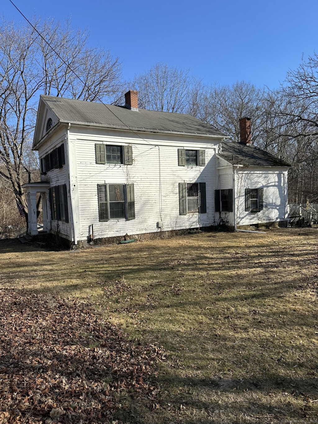 rear view of property featuring a lawn and a chimney