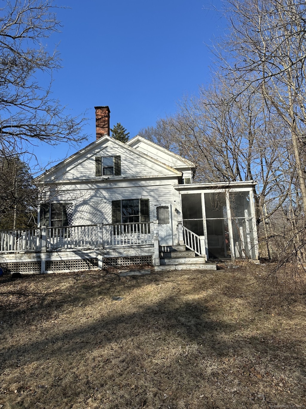 back of house with a chimney and a sunroom