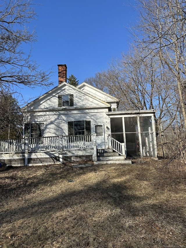 back of house with a chimney and a sunroom