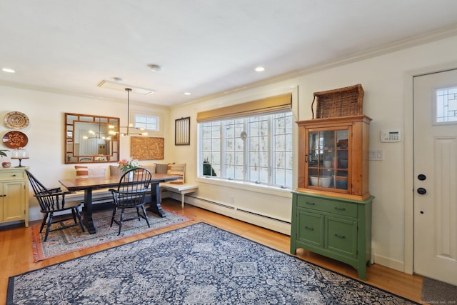 dining space with a chandelier, baseboard heating, crown molding, and wood finished floors