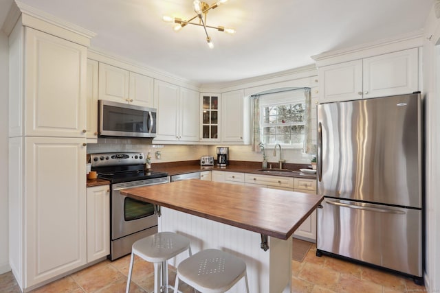 kitchen with a sink, wood counters, backsplash, stainless steel appliances, and glass insert cabinets