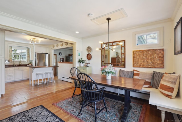 dining space featuring a notable chandelier, ornamental molding, light wood-style floors, and breakfast area