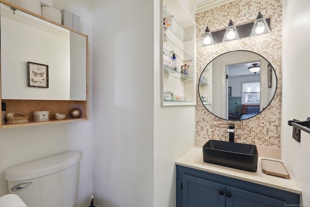 bathroom with decorative backsplash, toilet, and vanity