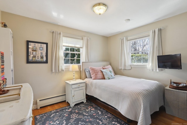 bedroom with light wood finished floors, multiple windows, and a baseboard heating unit