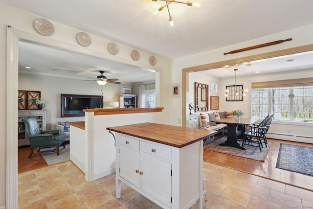 kitchen featuring a baseboard heating unit, decorative light fixtures, open floor plan, butcher block counters, and white cabinetry