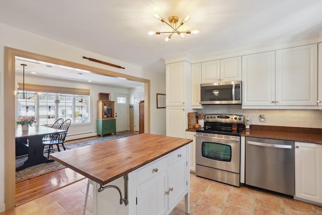 kitchen with wooden counters, decorative backsplash, appliances with stainless steel finishes, a notable chandelier, and white cabinetry