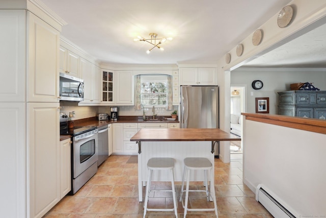 kitchen with a sink, wood counters, a kitchen breakfast bar, appliances with stainless steel finishes, and baseboard heating