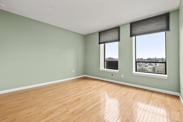 spare room with baseboards and hardwood / wood-style floors