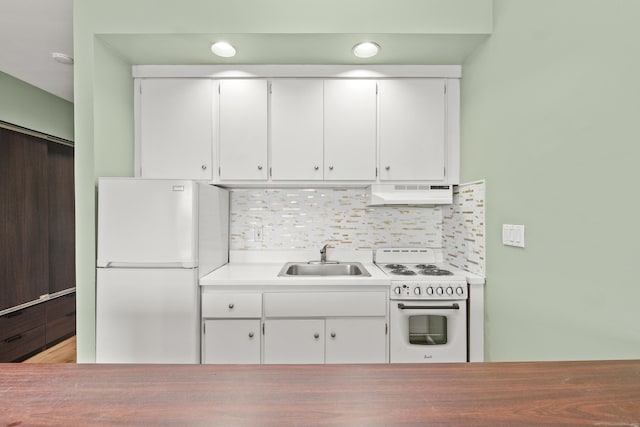 kitchen featuring white appliances, a sink, white cabinets, under cabinet range hood, and tasteful backsplash