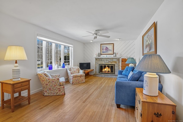 living room with a fireplace, baseboards, light wood finished floors, and ceiling fan