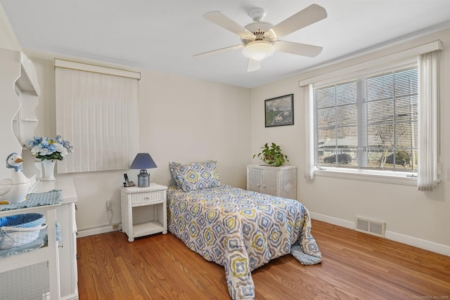 bedroom with visible vents, baseboards, wood finished floors, and a ceiling fan