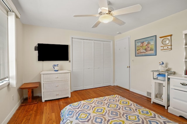 bedroom featuring wood finished floors, visible vents, baseboards, ceiling fan, and a closet