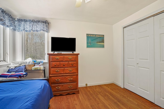 bedroom featuring light wood-type flooring, baseboards, a closet, and ceiling fan