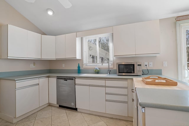 kitchen with a sink, stainless steel appliances, light countertops, white cabinets, and vaulted ceiling