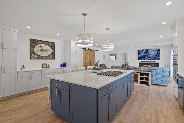 kitchen with a center island, open floor plan, light wood-type flooring, a barn door, and white cabinets