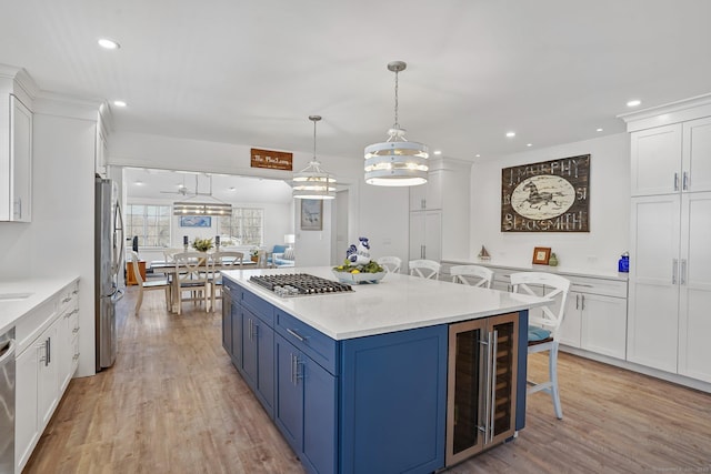 kitchen featuring blue cabinets, a kitchen breakfast bar, stainless steel appliances, wine cooler, and white cabinets