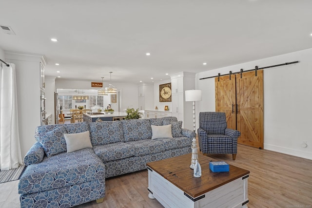 living area featuring visible vents, baseboards, a barn door, recessed lighting, and wood finished floors