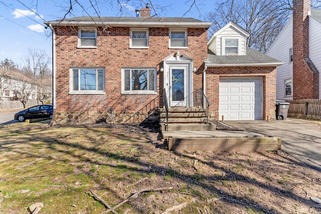 colonial house with brick siding, fence, aphalt driveway, a chimney, and a garage