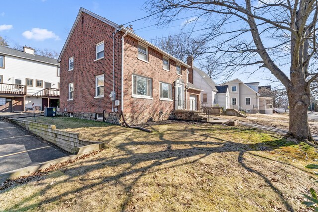 view of property exterior with a yard, brick siding, and a chimney