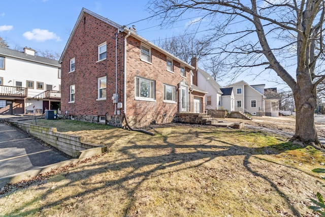 view of home's exterior featuring a yard, brick siding, and a chimney