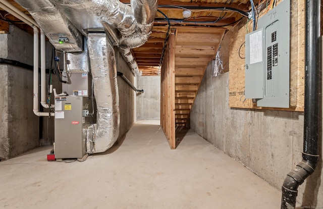 unfinished basement featuring electric panel and heating unit