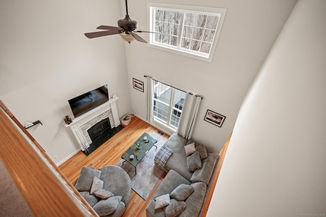 living room featuring visible vents, baseboards, a fireplace, wood finished floors, and a ceiling fan