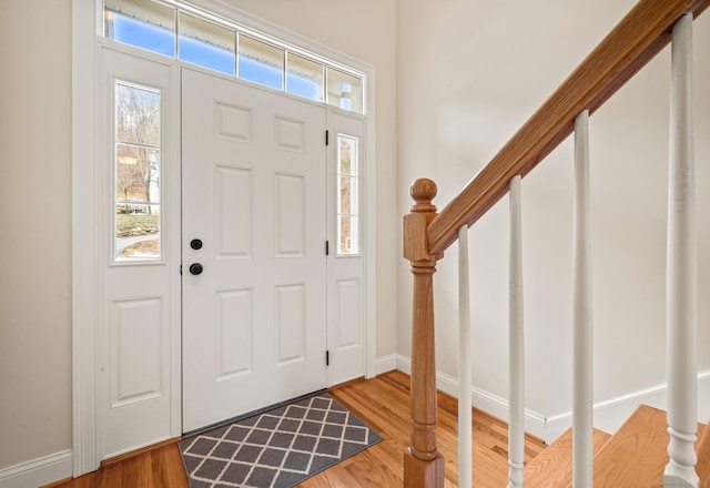 entryway featuring baseboards, wood finished floors, and stairs