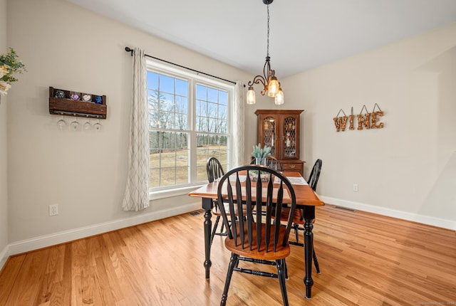 dining space featuring visible vents, a notable chandelier, light wood-style floors, and baseboards