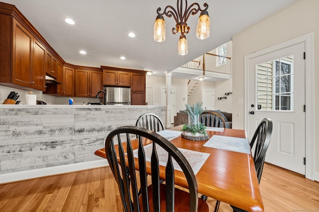 dining room featuring light wood-type flooring, recessed lighting, baseboards, stairs, and ornate columns