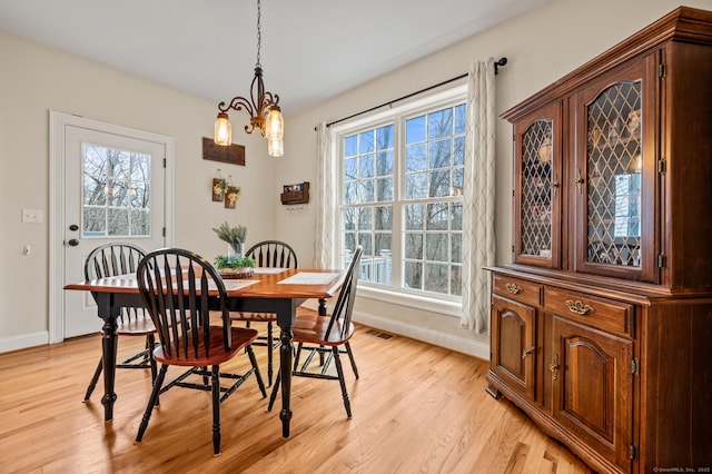 dining area featuring visible vents, baseboards, light wood-type flooring, and an inviting chandelier