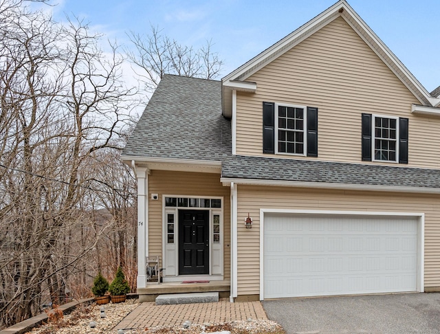 view of front facade featuring aphalt driveway, a garage, and a shingled roof