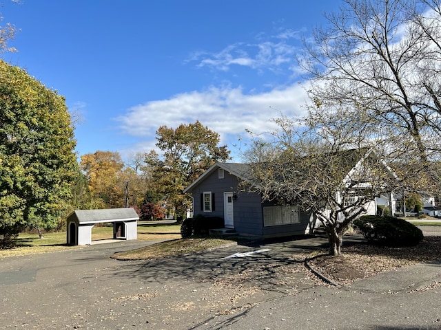 view of front of house with an outdoor structure, a carport, and driveway