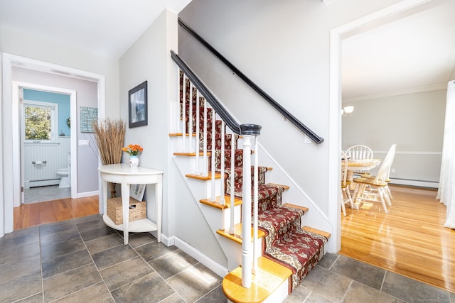 staircase with an inviting chandelier, stone tile floors, baseboards, and a baseboard radiator