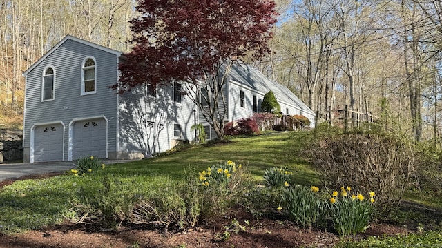 view of side of home with a garage, a yard, and aphalt driveway