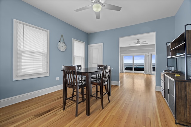 dining space with baseboards, light wood finished floors, and ceiling fan