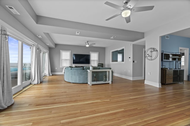 unfurnished living room with ceiling fan, baseboards, visible vents, and light wood-style floors