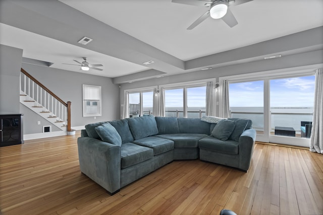 living room featuring a ceiling fan, light wood-style flooring, baseboards, visible vents, and stairway