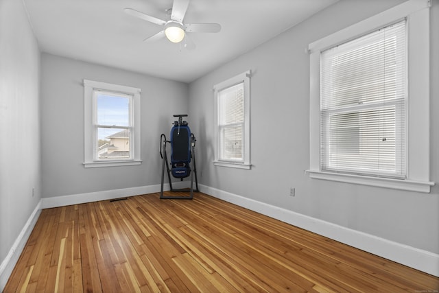 empty room featuring baseboards, a ceiling fan, visible vents, and light wood-style floors