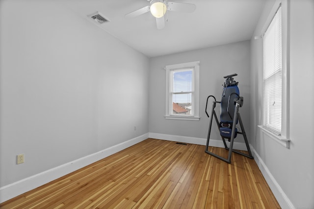 workout room with baseboards, ceiling fan, light wood-style flooring, and visible vents