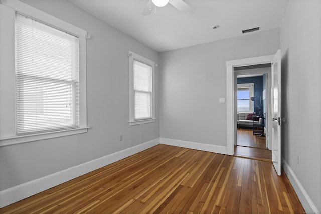 spare room featuring ceiling fan, hardwood / wood-style flooring, baseboards, and visible vents
