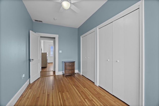unfurnished bedroom with multiple closets, baseboards, light wood-type flooring, and visible vents