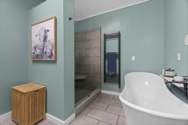 bathroom with baseboards, tile patterned flooring, a freestanding tub, and a stall shower