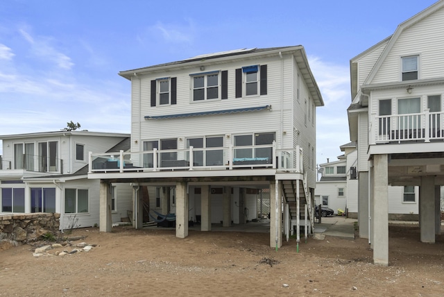 rear view of house featuring dirt driveway, a wooden deck, a carport, and stairs