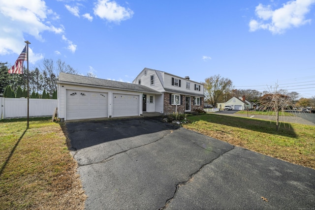 view of front of home with a gambrel roof, driveway, a front lawn, fence, and an attached garage