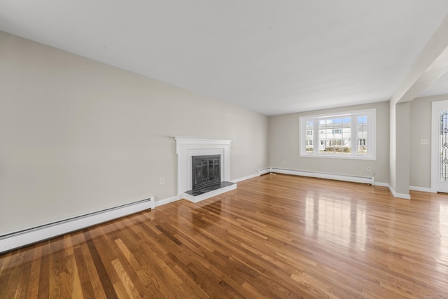 unfurnished living room featuring a glass covered fireplace, baseboards, baseboard heating, and wood finished floors