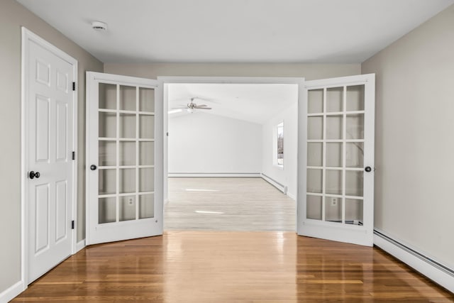 spare room featuring a baseboard heating unit, baseboard heating, wood finished floors, and a ceiling fan