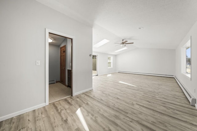 interior space with a baseboard heating unit, vaulted ceiling with skylight, and plenty of natural light