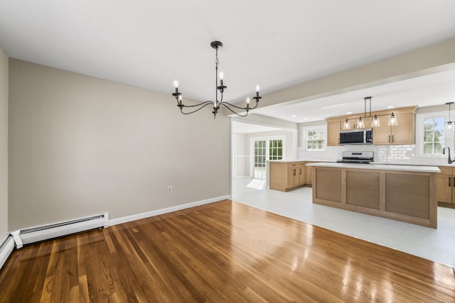 kitchen featuring tasteful backsplash, a center island, an inviting chandelier, appliances with stainless steel finishes, and light countertops